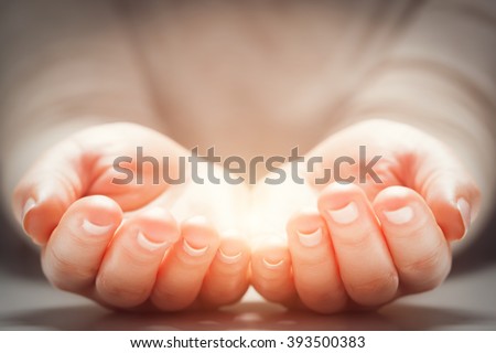 Light in woman\'s hands. Concepts of sharing, giving, offering, new life