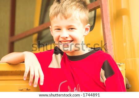 Young boy lean on yellow truck