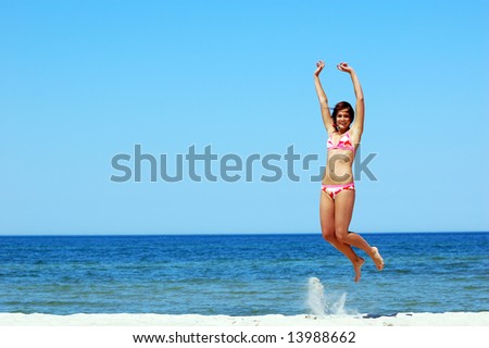 Young attractive woman jump on the beach