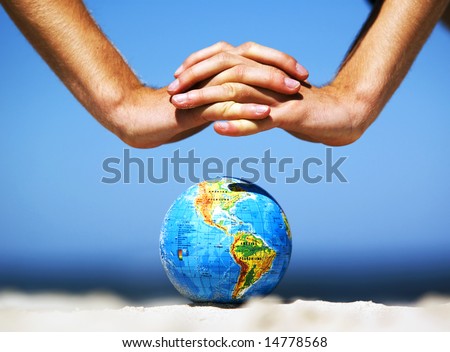 Earth globe on the beach and hands over it. Ideal for Earth protection concepts, recycling, world issues, enviroment themes