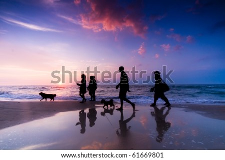 Family walk on the beach at sunset
