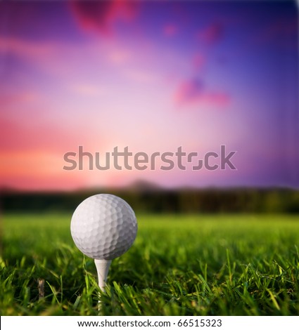 Golf ball on tee. Green grass, sunset.