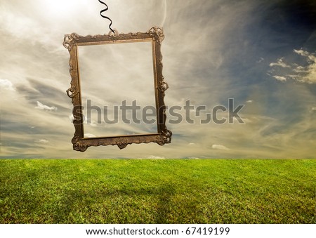 Empty retro frame hanging on poor grassy land. Conceptual.