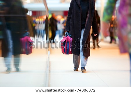 People in rush in a modern shopping mall. Close up and reflection of a woman walking