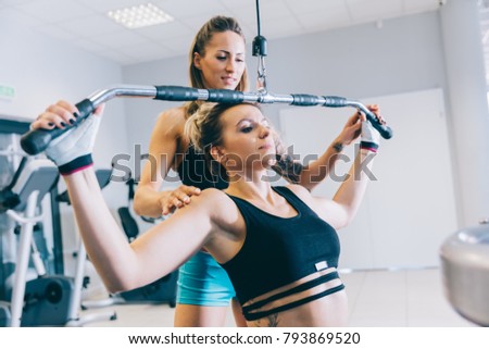 Woman helping other woman with her training. Gym & fit lifestyle.