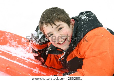 A Boy Smiling Laying on his Sled