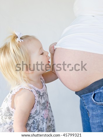 Little Girl Kissing New Sibling to Be