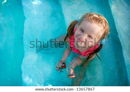 Happy little girl in a pool with big smile.