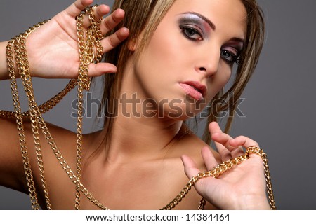 Beautiful girl with gold chain isolated on gray background.