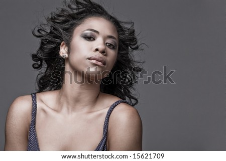 Beautiful young African-American fashion model in blue dress, with hair fluttering on wind.
