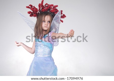 Cute little girl in good fairy costume. Halloween. Pretending to hold something in her hands.