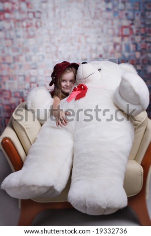 Little cute girl in red dress with big smile holding huge Teddy bear.