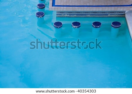 Blue warm water in hotel swimming pool with bar.