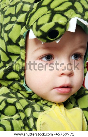 Little cute boy in green dinosaur costume.