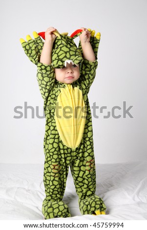 Little cute boy in green dinosaur costume.