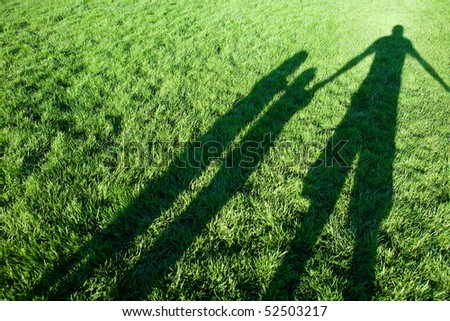 Father and child silhouettes on a green grass.