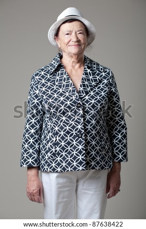 Happy senior lady posing on gray background.