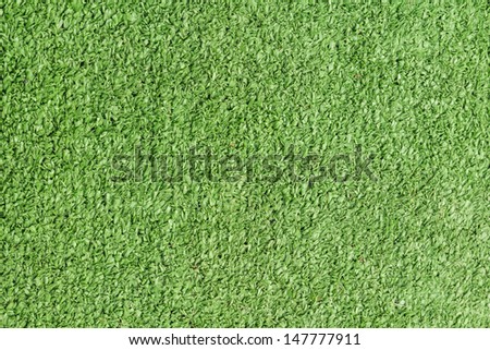 Background texture with fake grass in a public children playground, top view