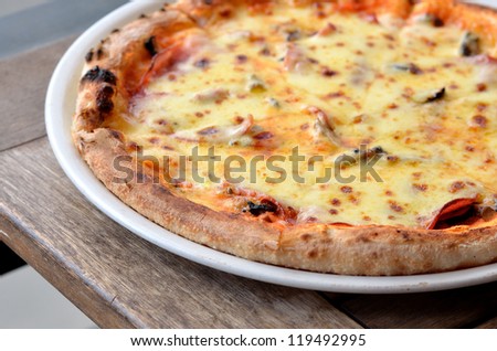 Thin crust pizza and various type of meat on wood table