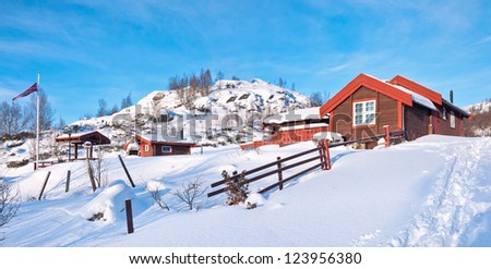 Norwegian small mountain cottage at a sunny winter day with snow in december with a simple fence of wood in the foreground