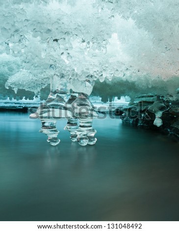 Ice cave between layers of ice in a river with icicles touching pure cold mountain water in the norwegian mountains at easter