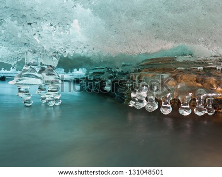 Ice cave between layers of ice in a river with icicles touching pure cold mountain water in the norwegian mountains at easter