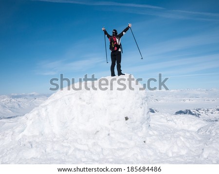 Female skier raising her arms at top of a summit in the norwegian mountains at easter with a magnificent view towards a chain of summits in the horizion