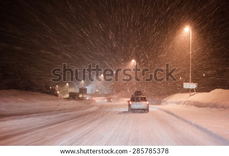 Traffic at Snowy weather With cars enlightened by street lights in a curve towards a church