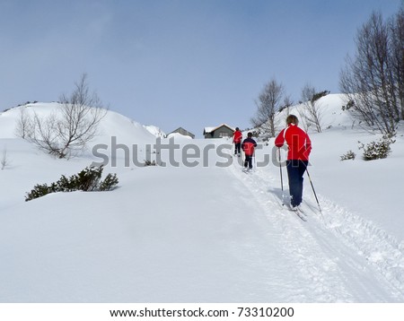 Family at ski at a light up hill heading towards a hunting lodge in the norwegian mountains at easter