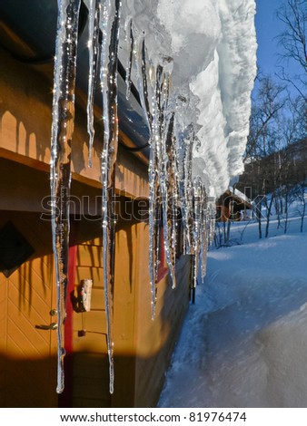 Roof icicles on a cottage at easter with snow enlightened by sun