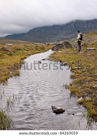 Woman resting close to a puddle on a cloudy day at early autumn in the norwegian mountains