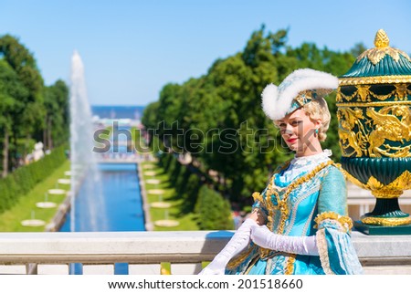 PETERHOF, RUSSIA - JUNE 15, 2014: Actress in ancient costume welcomes tourists in Petrodvorets at Peterhof. The Peterhof palace included in the UNESCO\'s World Heritage List.