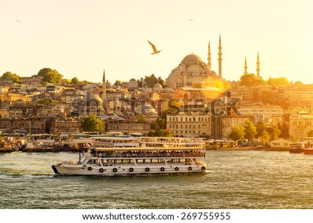 Tourist boat floats on the Golden Horn in Istanbul at sunset, Turkey