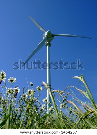 Wind turbine against a deep blue sky with giant daisies in foreground