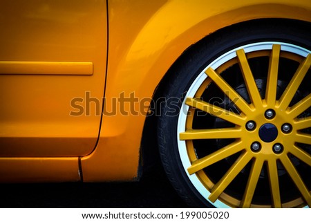 Detail of the front wheel of a yellow car.