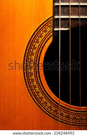 Color vertical detail of an old, acoustic guitar.
