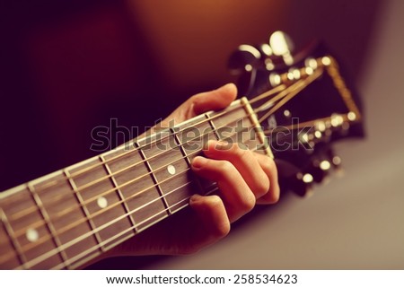 Color detail of hand playing of an old, acoustic guitar.
