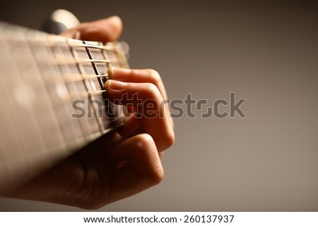 Color detail of hands playing of an old, acoustic guitar.
