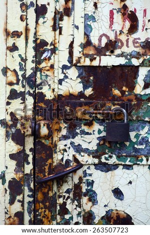 Color picture of a rusty padlock on a rusty metal door.