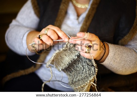 Color shot of a woman\'s hands using needles to knit.