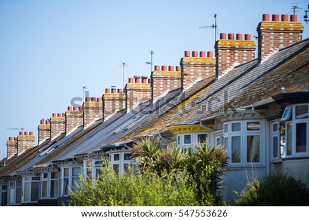 Color image of a typical English row of houses with chimneys.
