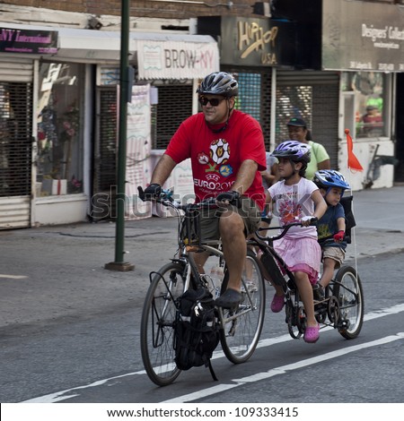 NEW YORK - AUGUST 04: Unidentified dad with 2 kids rides bicycle along Lafayette Street during Summer Streets sponsored by Department of Transportation in Manhattan on August 4, 2012 in NYC