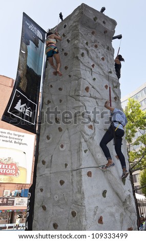 NEW YORK - AUGUST 04: Unidentified people climbing wall sponsored by REI store & The North Face clothing during Summer Streets sponsored by DOT on Lafayette Street in Manhattan on August 4 2012 in NYC