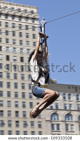 NEW YORK - AUGUST 04: Unidentified woman tries zip line sponsored by Fantasy World Entertainment during Summer Streets sponsored by DOT on Foley Square in Manhattan on August 4, 2012 in NYC