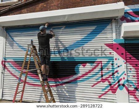 New York, NY - June 12, 2015: Artist Kristopher Kanaly paints graffiti on the wall in Queens Astoria neighbourhood