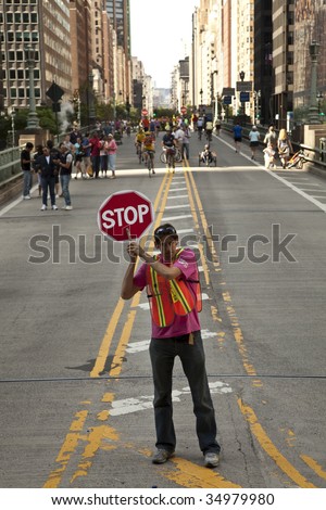 NEW YORK - AUGUST 8: A crossing guard with stop sign directs traffic during first day of summer streets festival on 4th avenue August 8, 2009 in Manhattan, New York.
