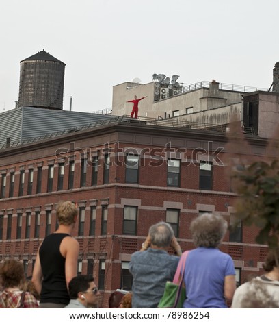 NEW YORK - JUNE 10: Dancer of Trisha Brown Dance Company performs Roof Piece on rooftops of buildings along Highline Park with people watching on June 10, 2011 in New York City