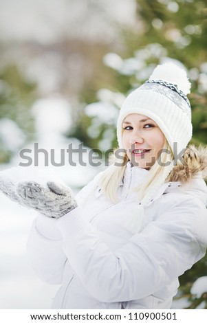A Young Woman Wearing Warm Winter Clothes And Hat Holding Snow In Her Hands, vertical format