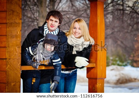 Beautiful family in warm clothes standing on the porch of his house in winter, horizontal photo
