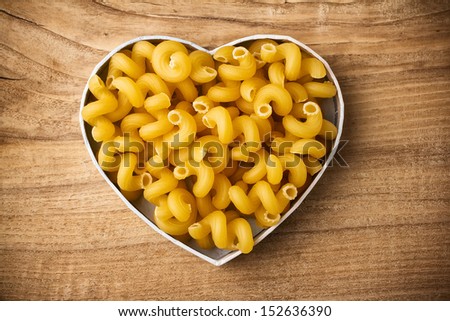 Pasta, the heart-shaped box. Wooden surface.